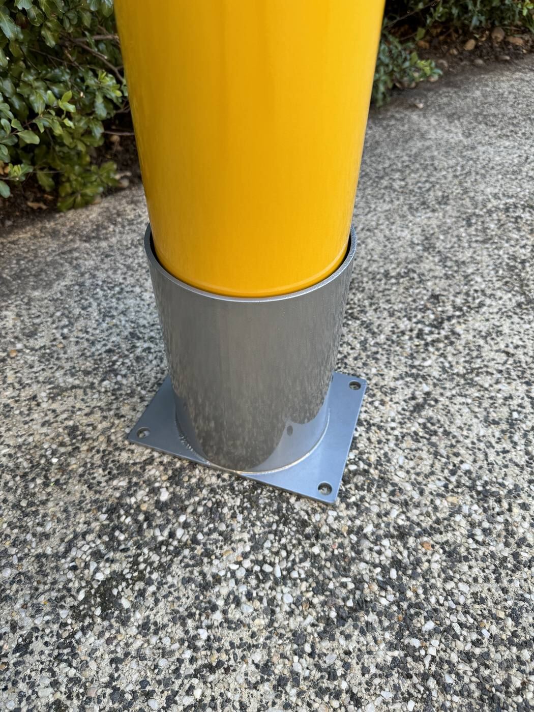 Removable bollard installed into an in-ground sleeve on a concrete driveway